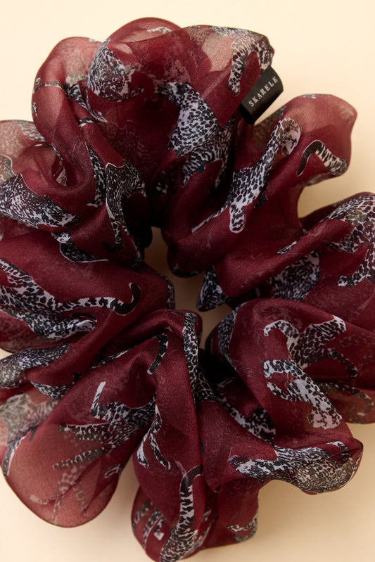 Close up of burgundy silk organza scrunchie with silver cheetah pattern