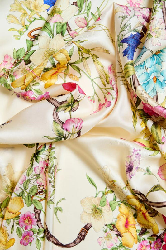 A floral patterned silk scarf displayed on a surface.