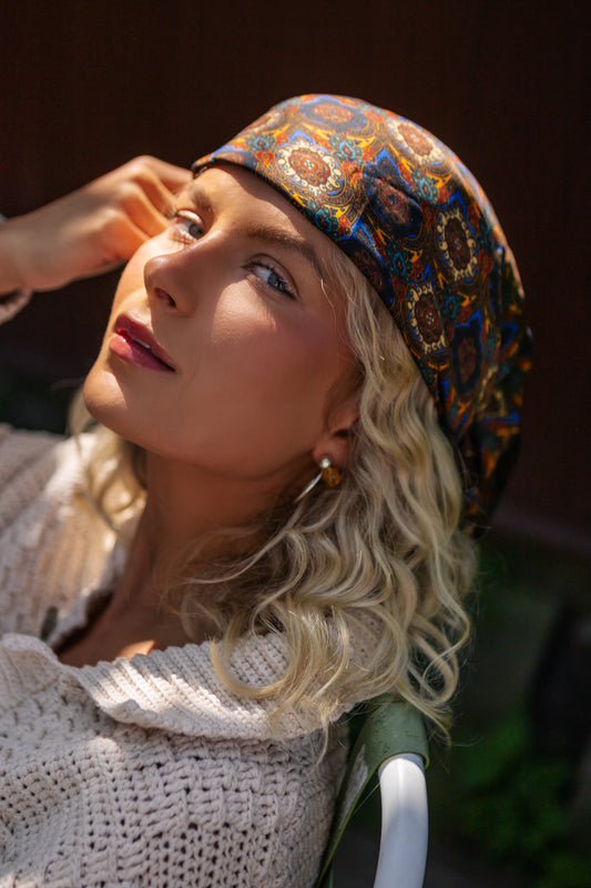 radiant blonde woman basks in the sun, wearing a vibrant patterned bohemian silk headscarf and a cozy crocheted top, evoking a carefree, summery vibe.