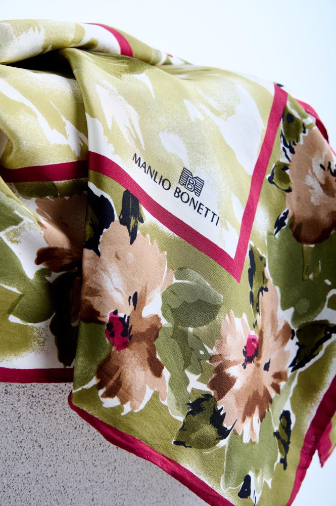 Close-up of a luxury Manlio Bonetti silk scarf featuring a vintage floral print with brown and pink flowers on a sage green background, finished with a bold magenta border.