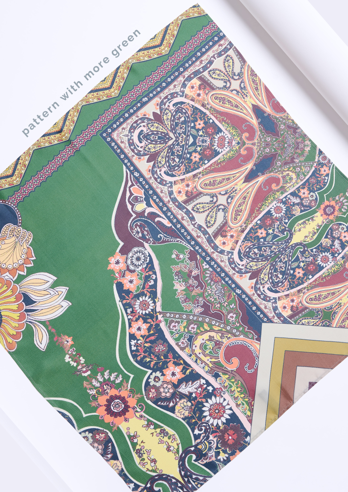 A fragment of a silk scarf featuring a bohemian floral and paisley pattern on a dominant rich green background. The photo shows detailed oriental-style compositions with coral, yellow, and blue accents, along with decorative corner frames, highlighting the accessory's aesthetic and high quality.