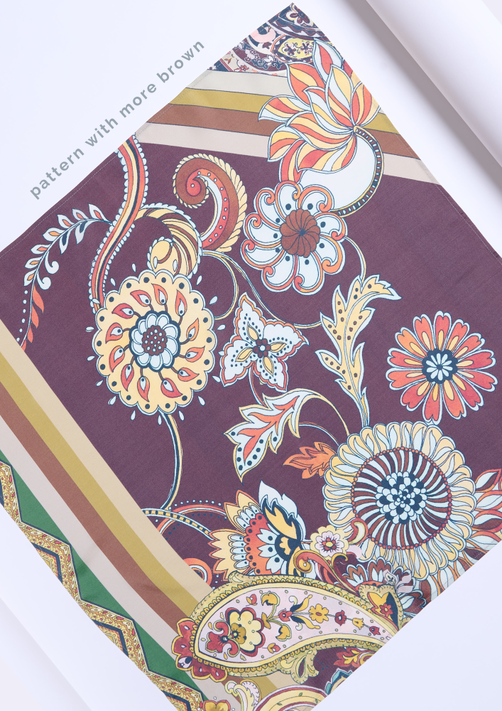 fragment of a silk scarf featuring a bohemian, Oriental-inspired pattern on a rich brown-burgundy background. The design is characterized by lush floral compositions, stylized paisley elements, and mandalas intertwined with coral, mustard, green, and white tones. The edges are adorned with contrasting diagonal color stripes, adding a modern, geometric accent to the accessory.