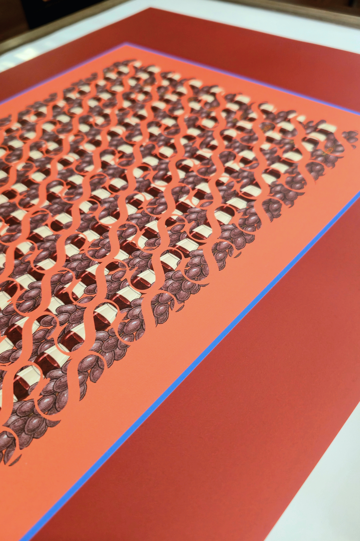 Perspective view close-up of the "Evening deep red" art print, highlighting the high-quality print finish, terracotta center with dark grapes, wine glasses, and blue border accent line.