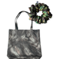 A set featuring a grey patterned water repellent cotton tote bag and a matching dark brown and green details mid-size scrunchie on a white background.