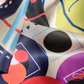 Detailed macro view of premium silk scarf fabric texture. Abstract modern graphic design with vibrant red, purple, and green circles from the Skarele luxury accessory collection.