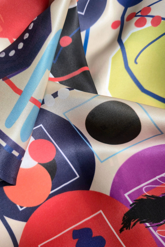 Detailed macro view of premium silk scarf fabric texture. Abstract modern graphic design with vibrant red, purple, and green circles from the Skarele luxury accessory collection.