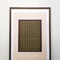 Interior mockup of the beige digital art print framed in a thin dark wooden frame with a white passe-partout mat, featuring green tea cups and leaves pattern, resting on a wooden table against a clean white wall
