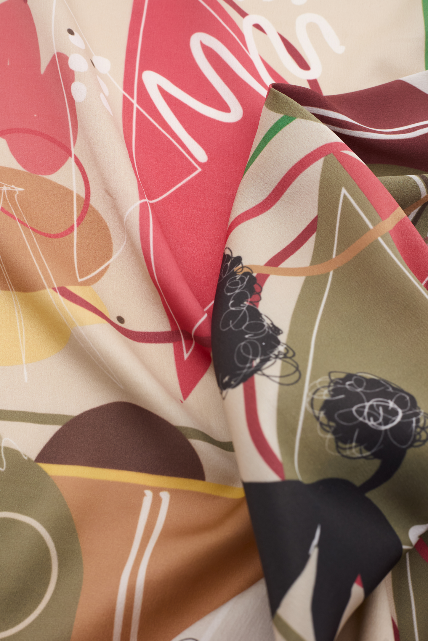 Macro shot of the MUSE Silk Scarf in Chestnut Brown, emphasizing the rich pigmentation of the fabric's dyes. The abstract pattern features terracotta red triangles, ochre circles, and dark line art. The way the fabric bunches shows its lightweight and fluid drape, perfect for luxury accessory lovers.