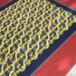 Perspective view close-up of the "Movement dynamic blue" art print, highlighting the high-quality print finish, dark navy center with vintage tennis rackets and yellow tennis balls, teal border line, and wooden frame edge.