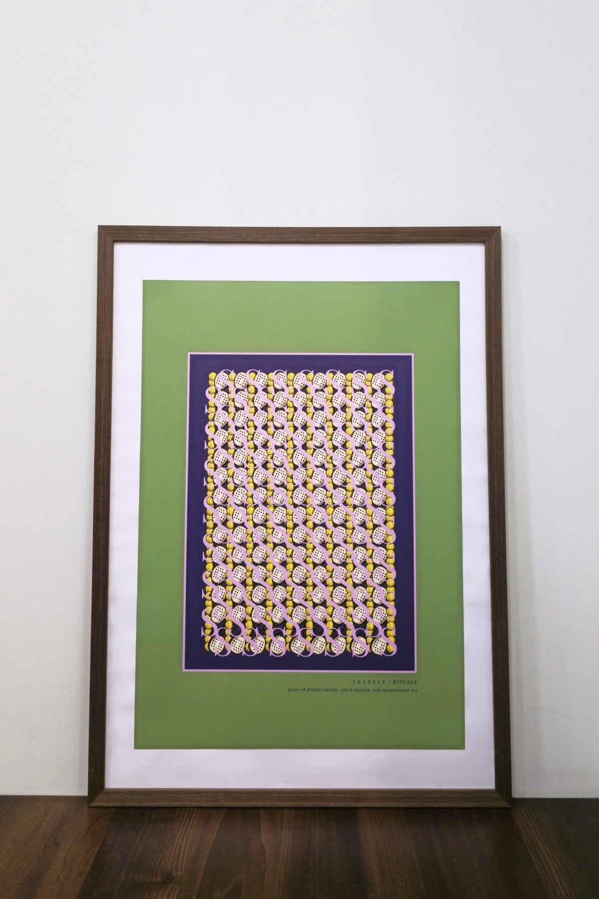interior mockup of the "Movement citrus yellow" digital poster framed in a thin dark wooden frame with a white passe-partout mat, featuring padel rackets and  balls pattern, resting on a wooden table against a clean white wall.