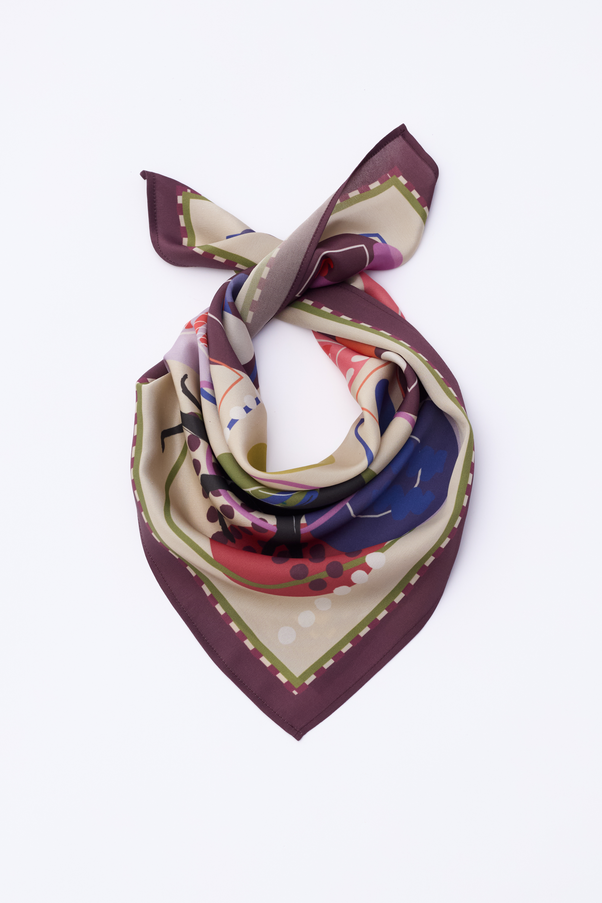 The NOMAD Velvet Plum Silk Scarf is shown folded in a neck-tie arrangement on a white background. The scarf features a wide, deep plum purple border with an intricate green and white dashed inner line. The center reveals a sophisticated abstract pattern with shades of magenta, navy blue, and sage green. A black sighthound silhouette is partially visible within the artistic folds of the smooth silk fabric.