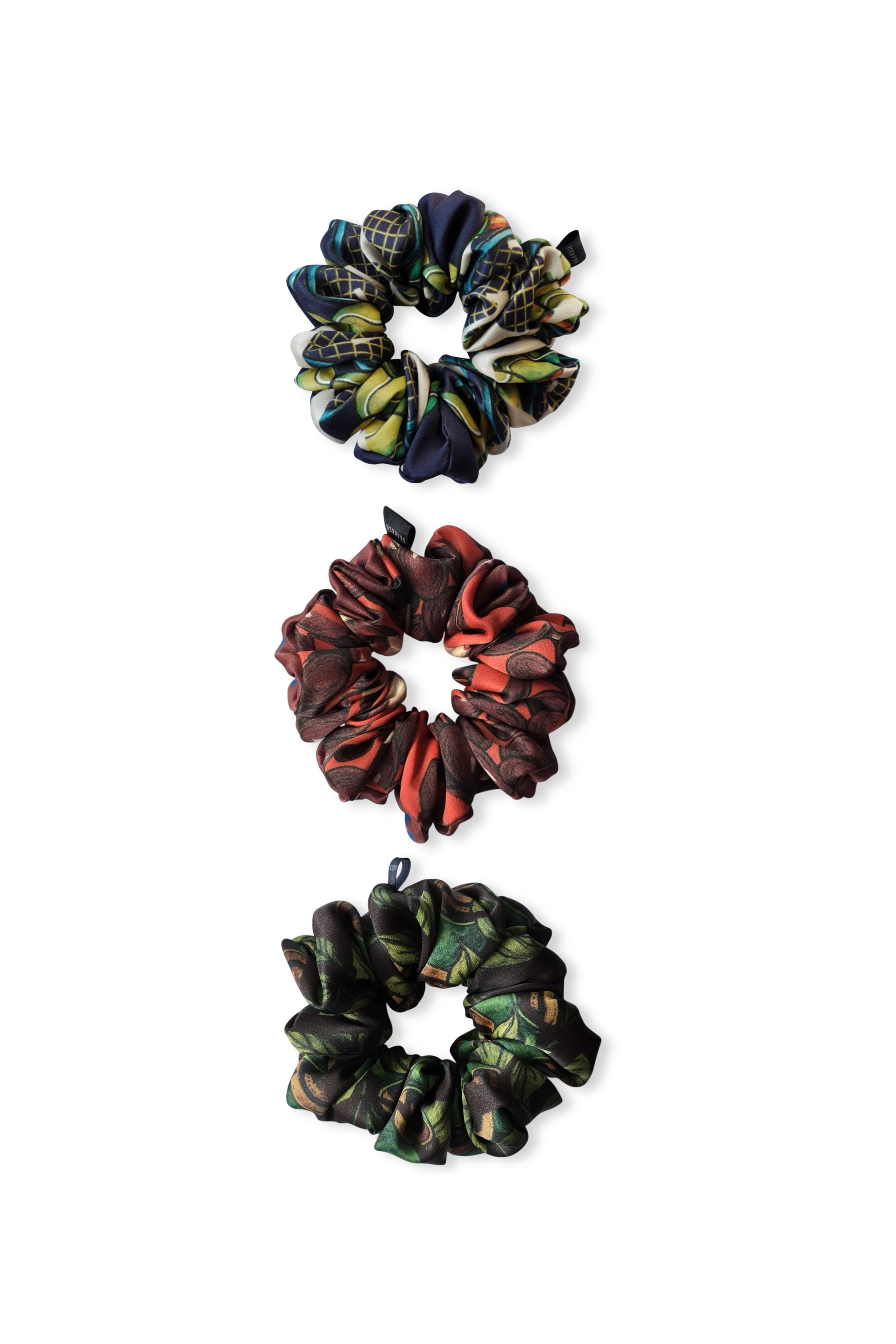 Three patterned silk scrunchies on a white background