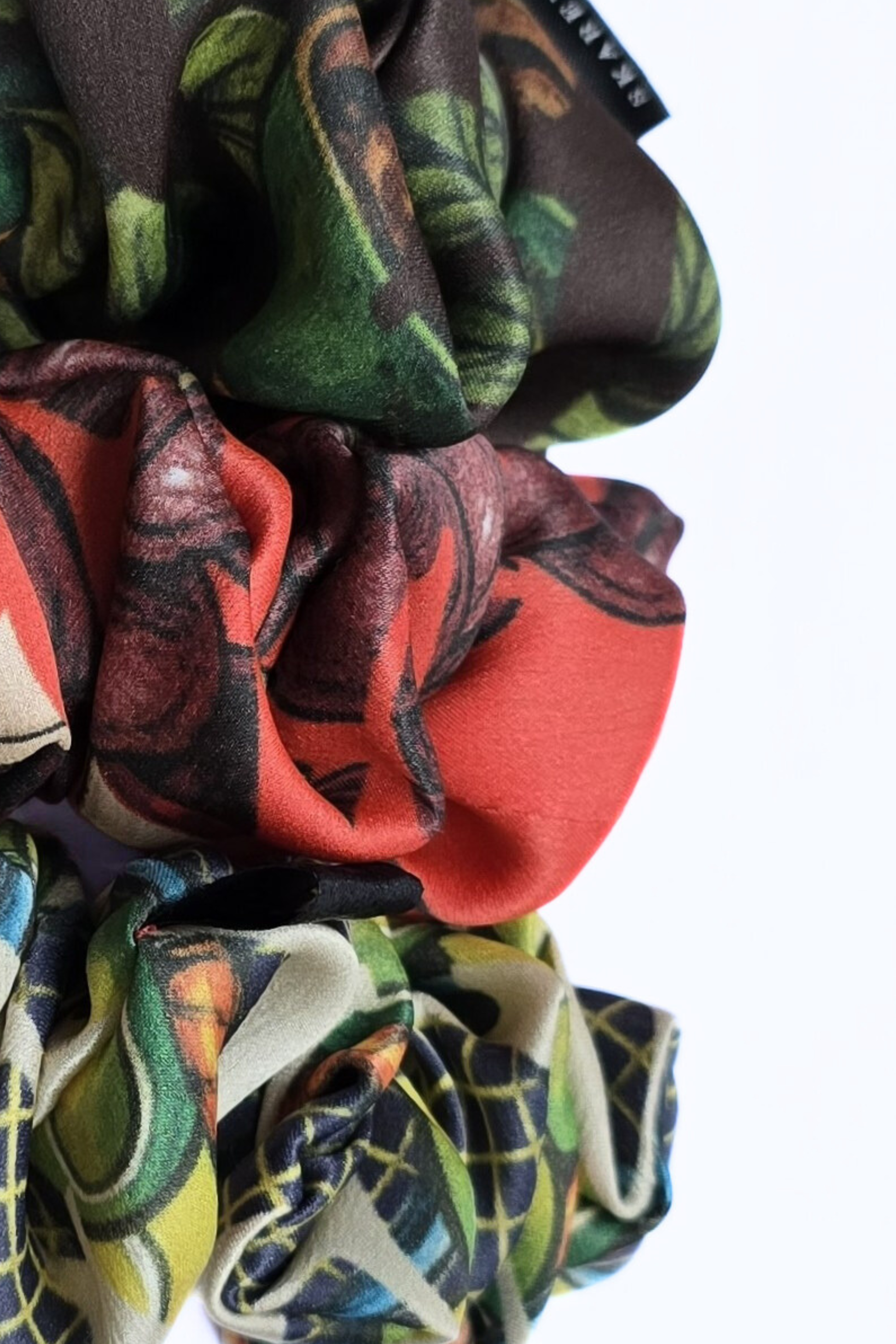 Close up of colorful patterned silk scrunchies on a white background