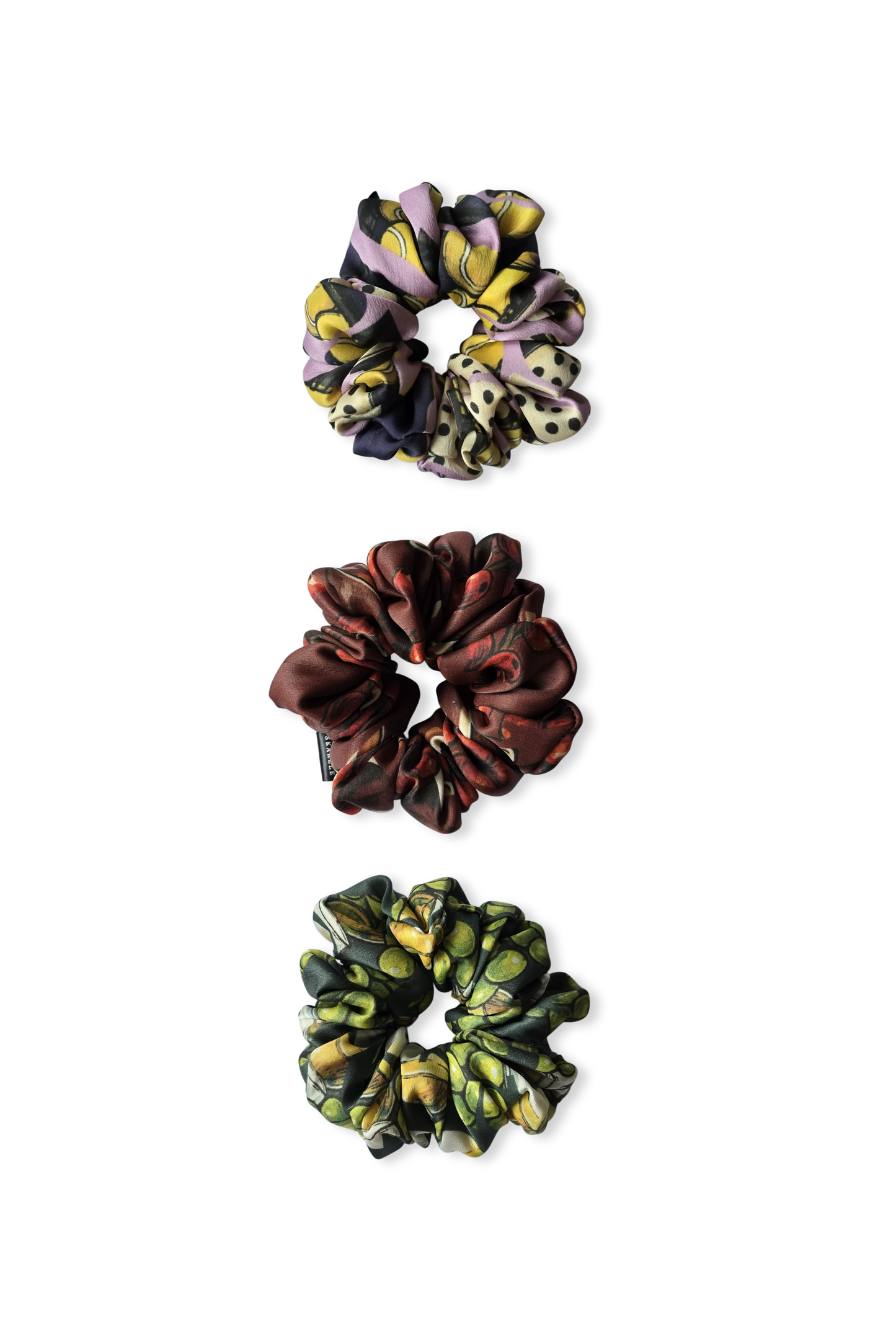 Three colorful silk scrunchies on a white background