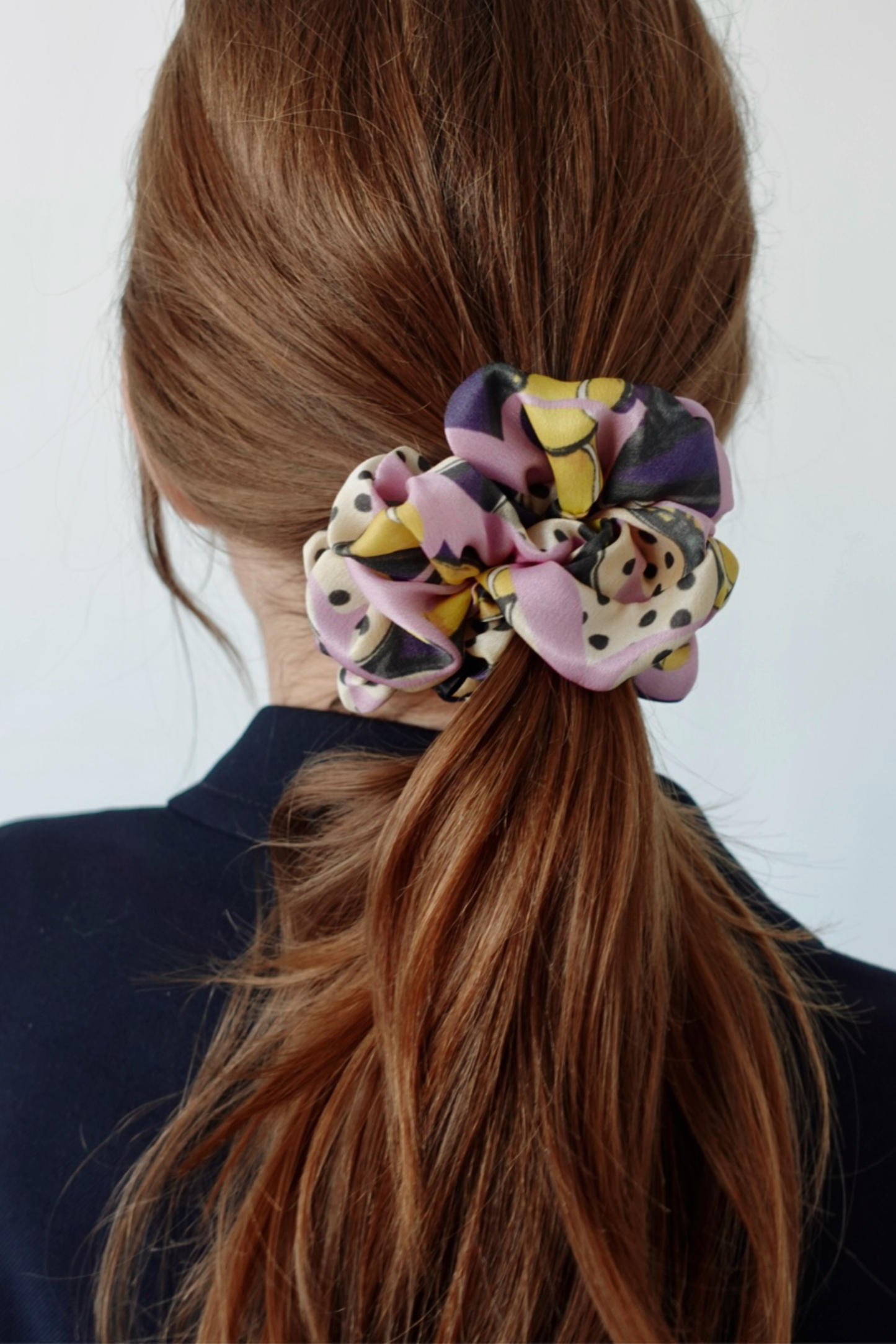 Multicolored MOVEMENT silk scrunchie in a ponytail against a white background