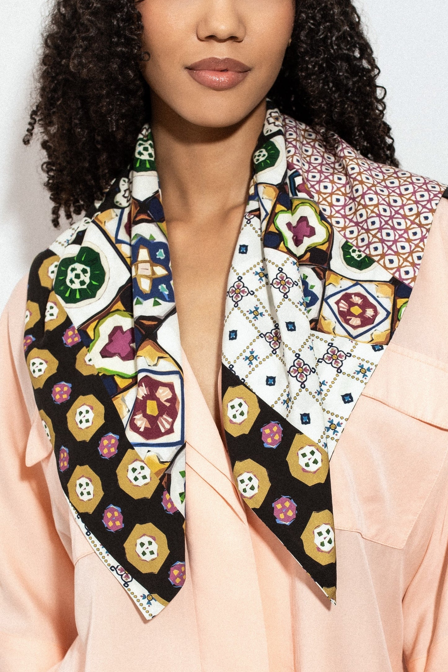 Woman wearing a colorful patterned viscose scarf on a plain background