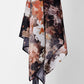 Hanging abstract scarf with a bold, textured pattern in warm tones of black, orange, and white against a plain white background.