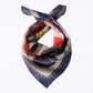 A square silk scarf with an abstract pattern, tied in a knot against a plain white background. The scarf features a navy blue border and a multicolor interior with beige, red, blue, and yellow shapes.