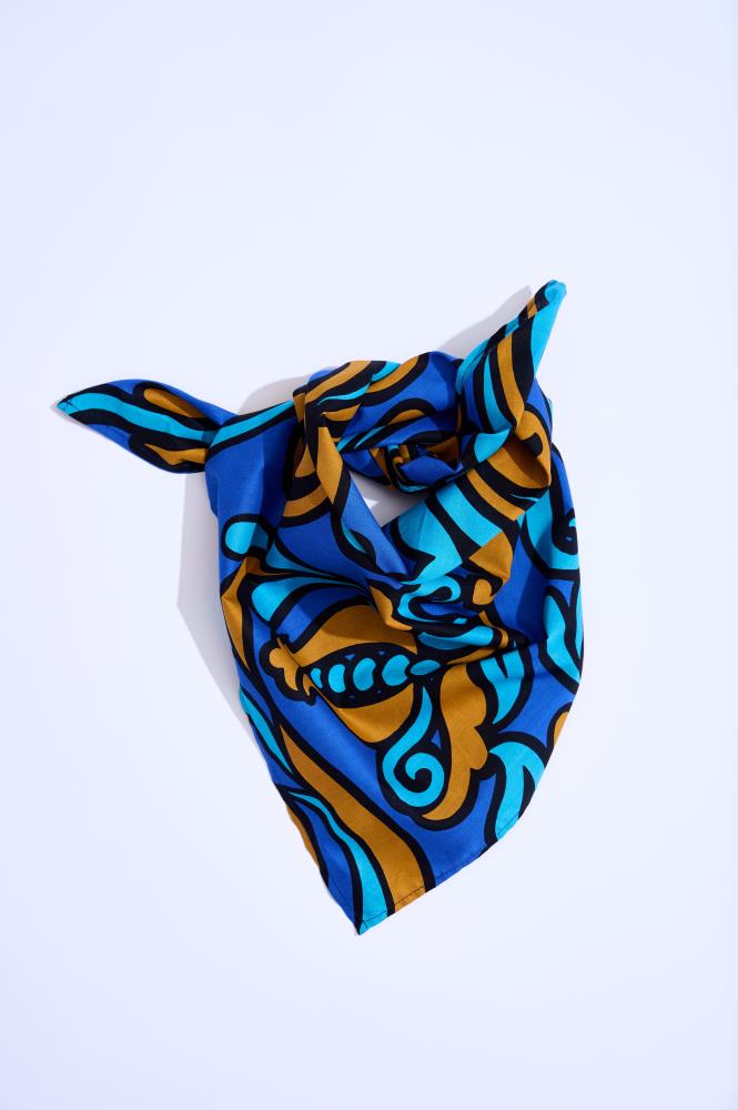 A square silk scarf folded into a triangle and tied with a knot at the top, photographed against a clean white background. The scarf features a bold Baroque-style pattern with royal blue, cyan, and bronze elements separated by striking black outlines.
