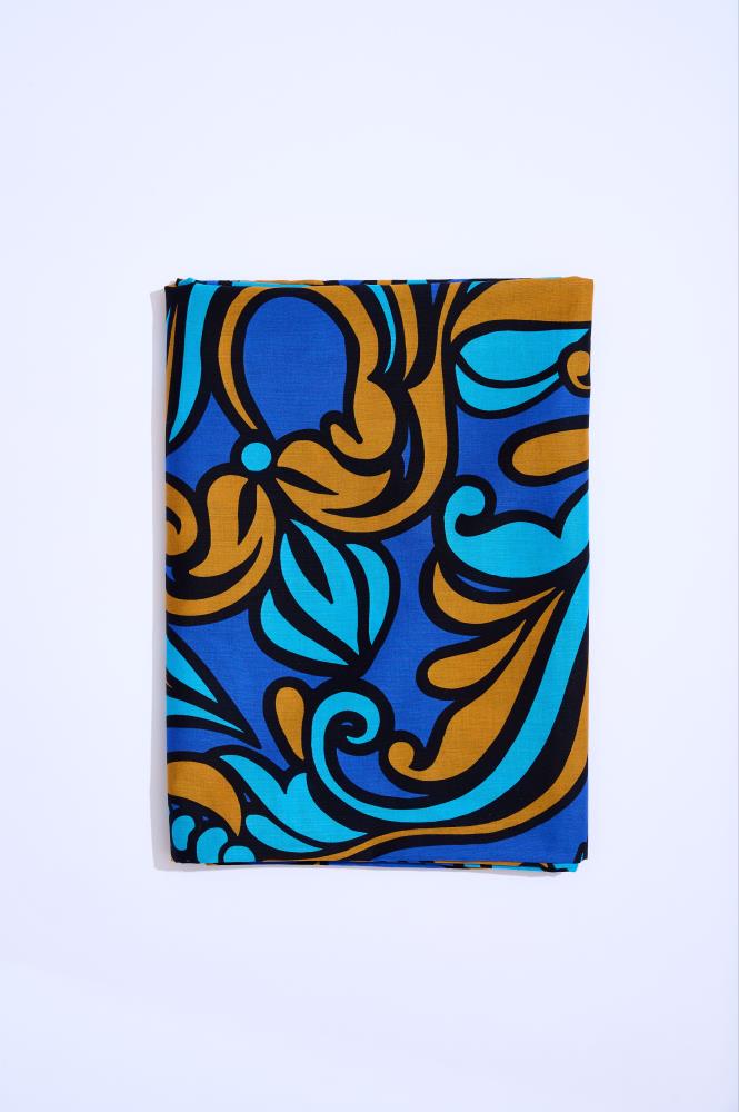A rectangular folded piece of fabric placed vertically against a clean white background. The material features a large, decorative pattern with royal blue, cyan, and bronze motifs, outlined in bold black contours.