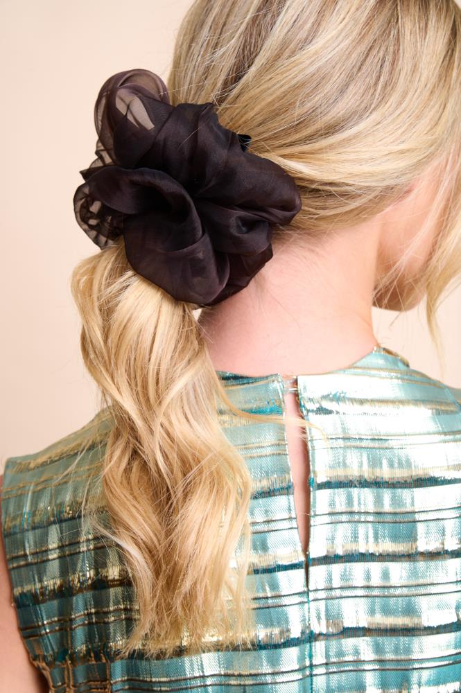A silk scrunchie in a rich chocolate brown color, displayed on a model's hair.