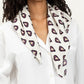 Woman wearing a white blouse with a patterned scarf around her neck against a white background