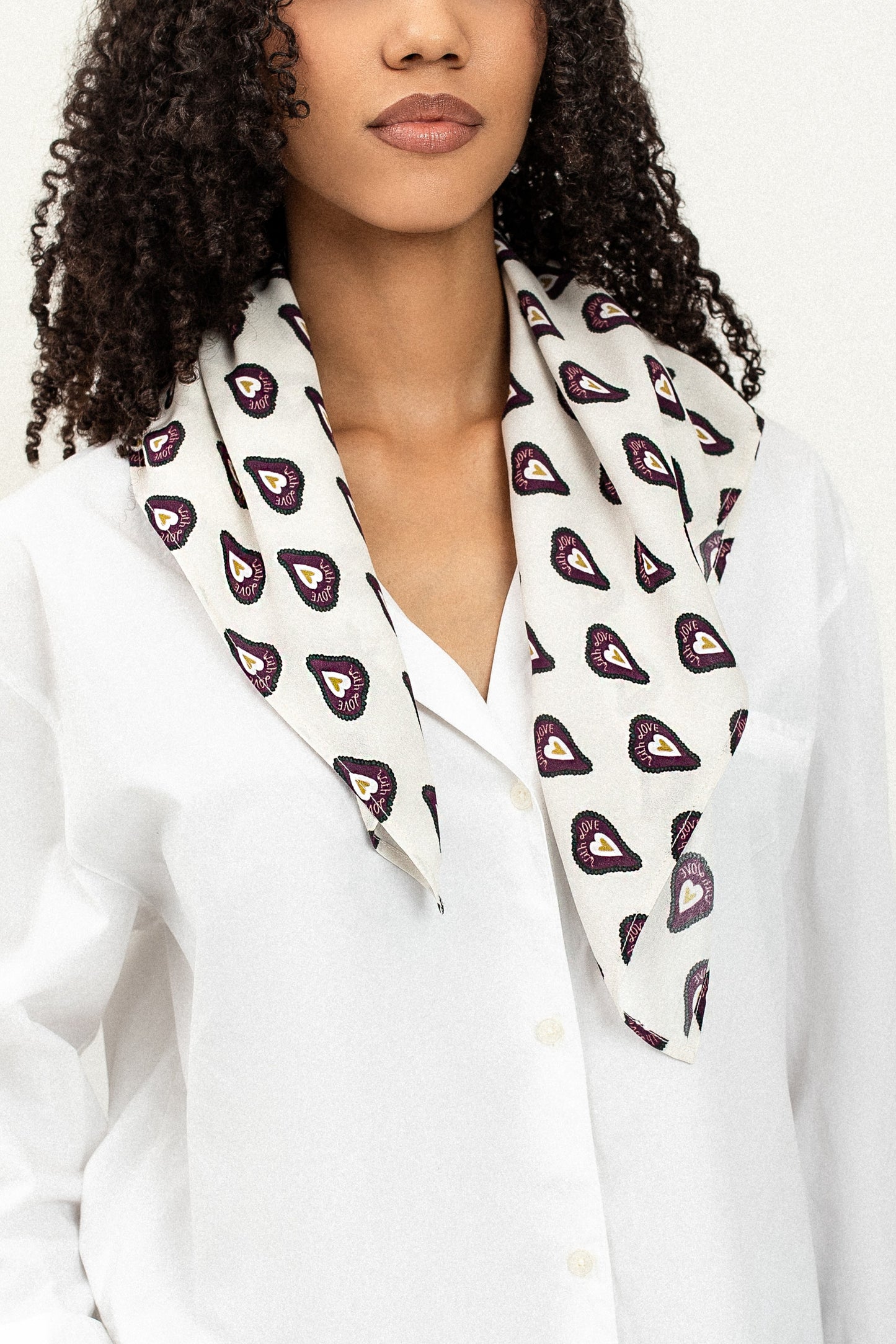 Woman wearing a white blouse with a patterned scarf around her neck against a white background