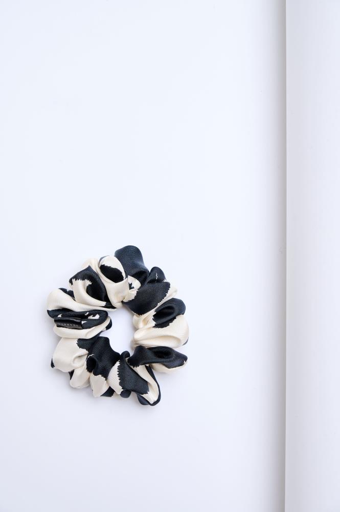 A mid-size black and white silk scrunchie on a light background.