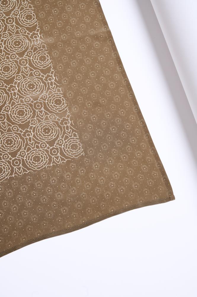 A photo showing an unfolded corner of a brownish silk scarf against a white background. The fabric is decorated with two different but matching light patterns: one part features larger floral motifs, while the other has fine dots and ornaments. The precise hem and smooth material texture highlight the product's quality and elegant design.