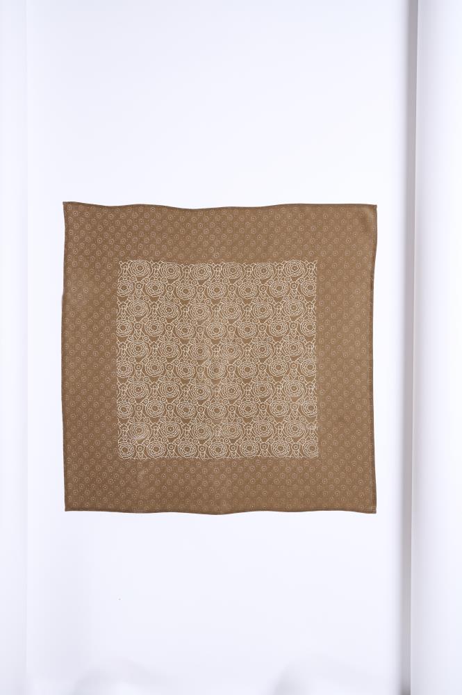 A square, brownish silk scarf neatly laid out on a white background. The accessory features a symmetrical design: the center square is decorated with a dense light floral pattern, while the surrounding wide border is patterned with fine, repeating dots and ornaments. The minimalist composition and soft sheen of the fabric highlight the elegant and classic style of the product.
