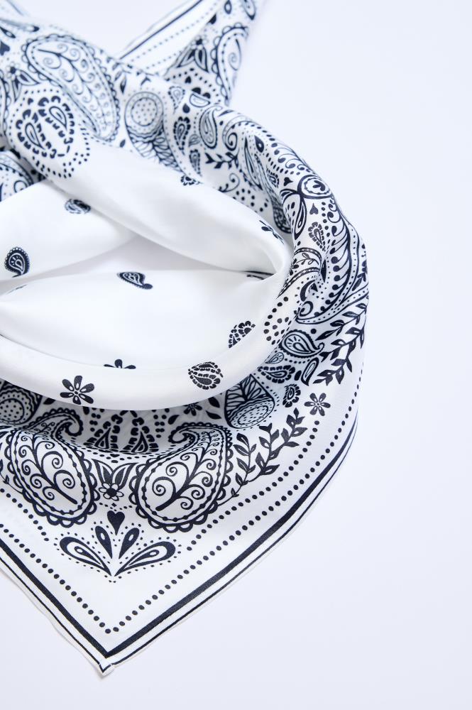 A close-up image of a white viscose scarf with a black paisley pattern.