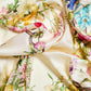 A floral patterned silk scarf displayed on a surface.
