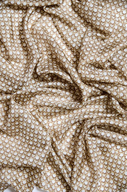 A silk scarf with a geometric pattern in muted tones of beige, brown, and champagne.