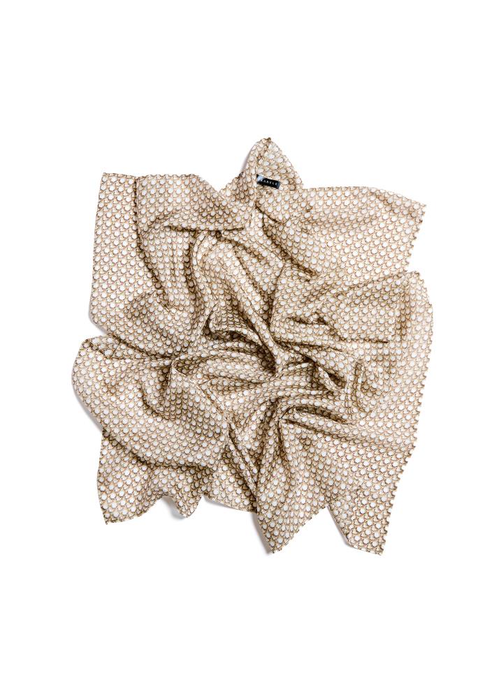 A beige silk scarf with a dotted pattern, draped and displayed on a plain background.