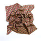 A silk scarf with a geometric pattern displayed on a flat surface.