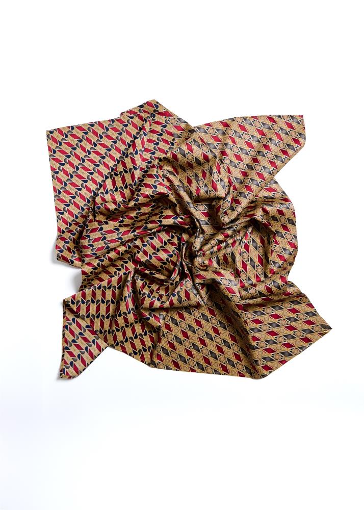 A silk scarf with a geometric pattern displayed on a flat surface.