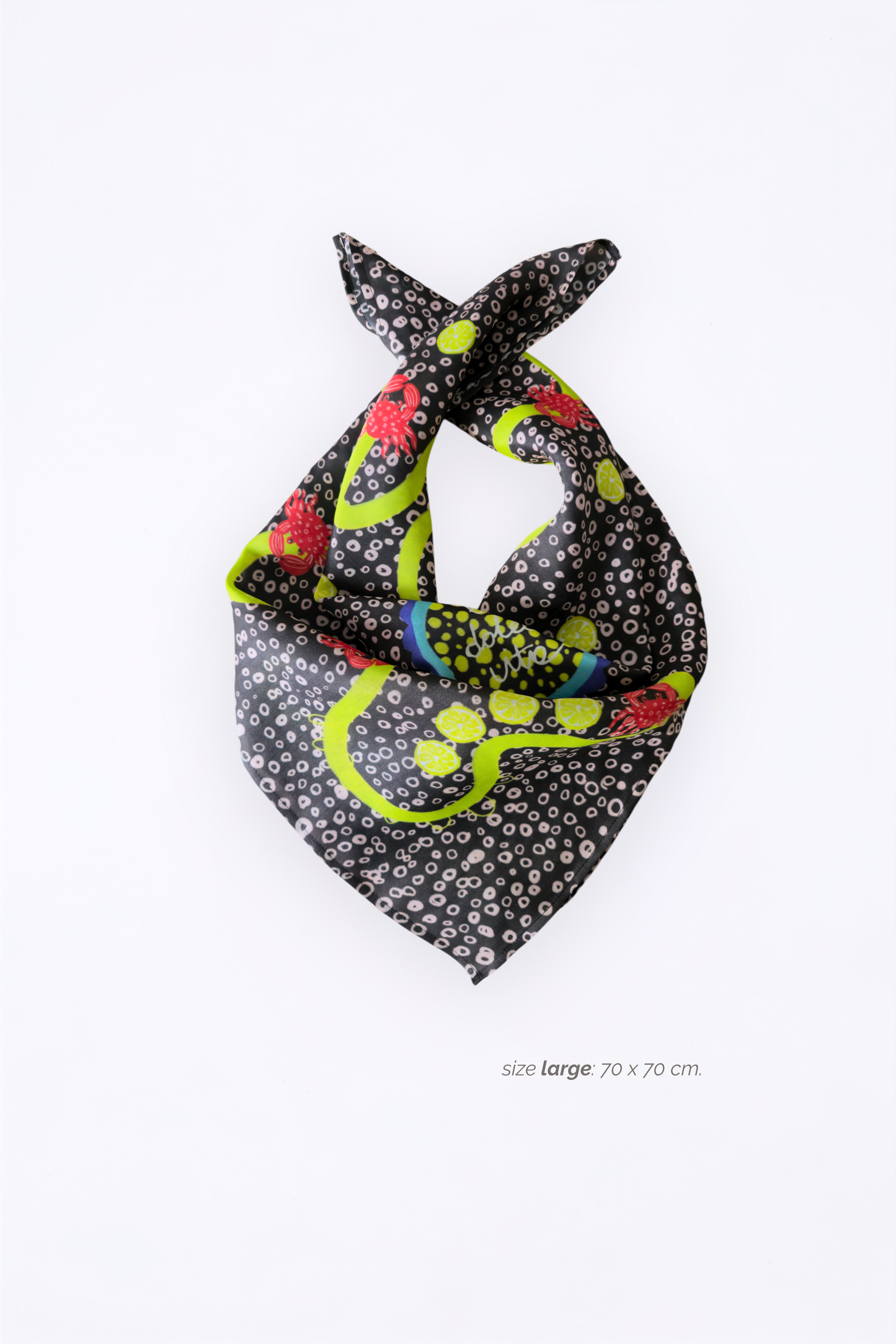 Product shot of a large 70x70 cm luxury viscose & silk blend blend scarf folded in a loose loop. Highlights the draped greyish-brown satin texture with a playful summer crab and lemon motif on a white backdrop.