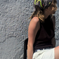 Woman styling the dark greyish-brown La Dolce Vita silk bandana on her head. Summer lifestyle fashion shot showcasing a luxury patterned headscarf on a sunny day.