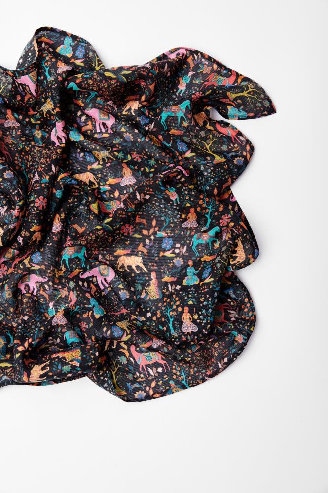 A colorful, crumpled scarf featuring whimsical animal and foliage patterns on a dark background, conveying a playful and vibrant tone.