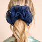 Navy blue silk organza scrunchie on a person with blonde hair against a beige background