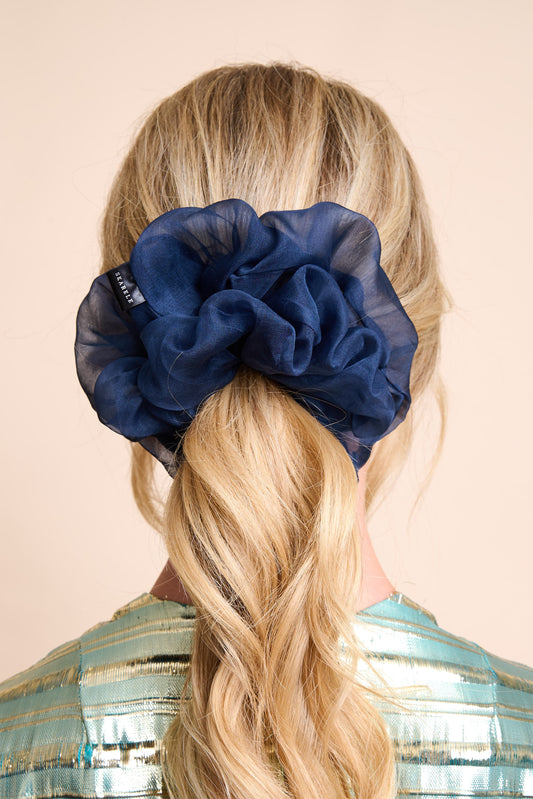 Navy blue silk organza scrunchie on a person with blonde hair against a beige background