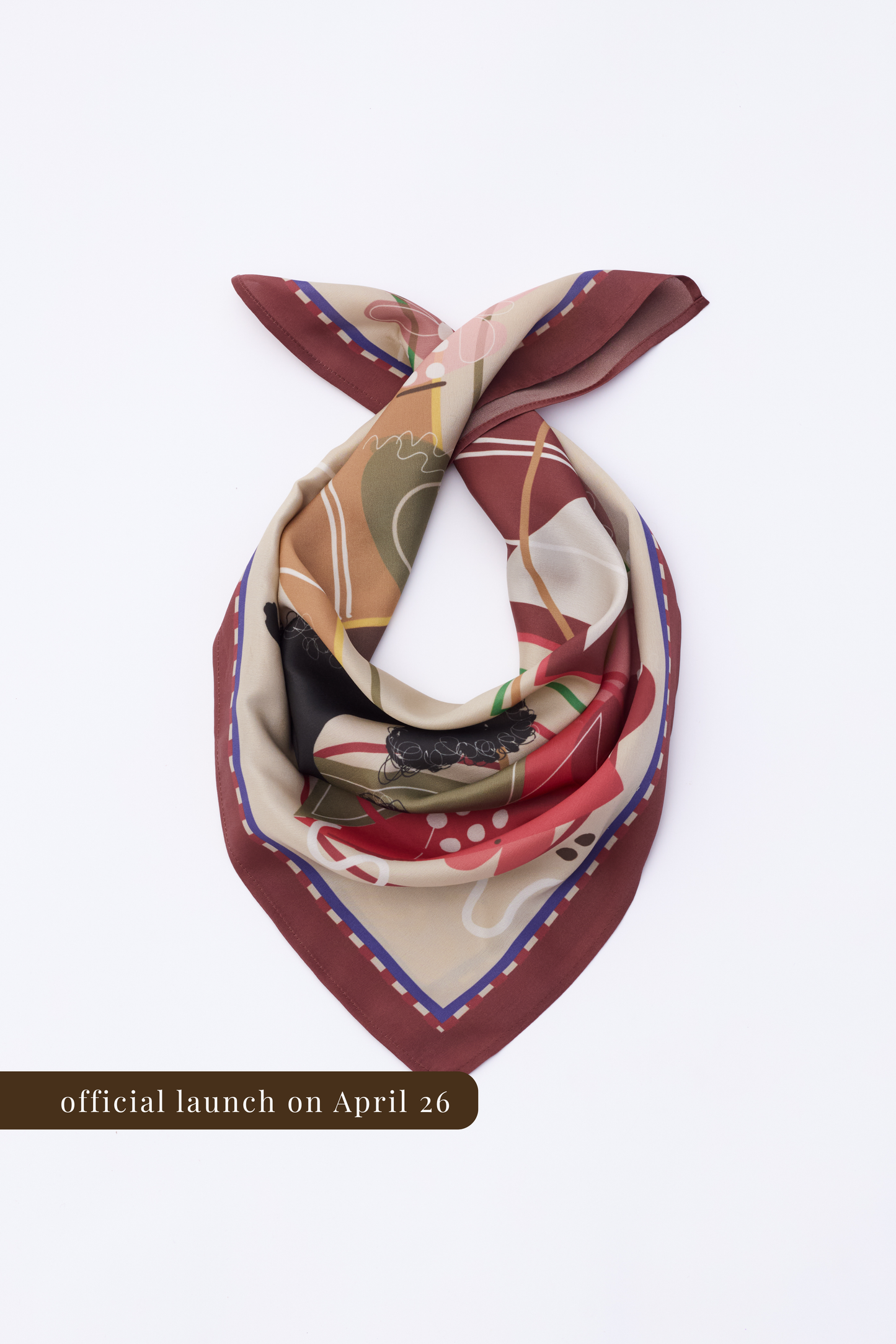 Product shot of a patterned silk neckerchief displayed on a white background. The scarf is arranged to show its soft, lightweight texture and artistic graphic elements, including stylized line art and color blocks. The lighting is bright, highlighting the fabric's subtle sheen.