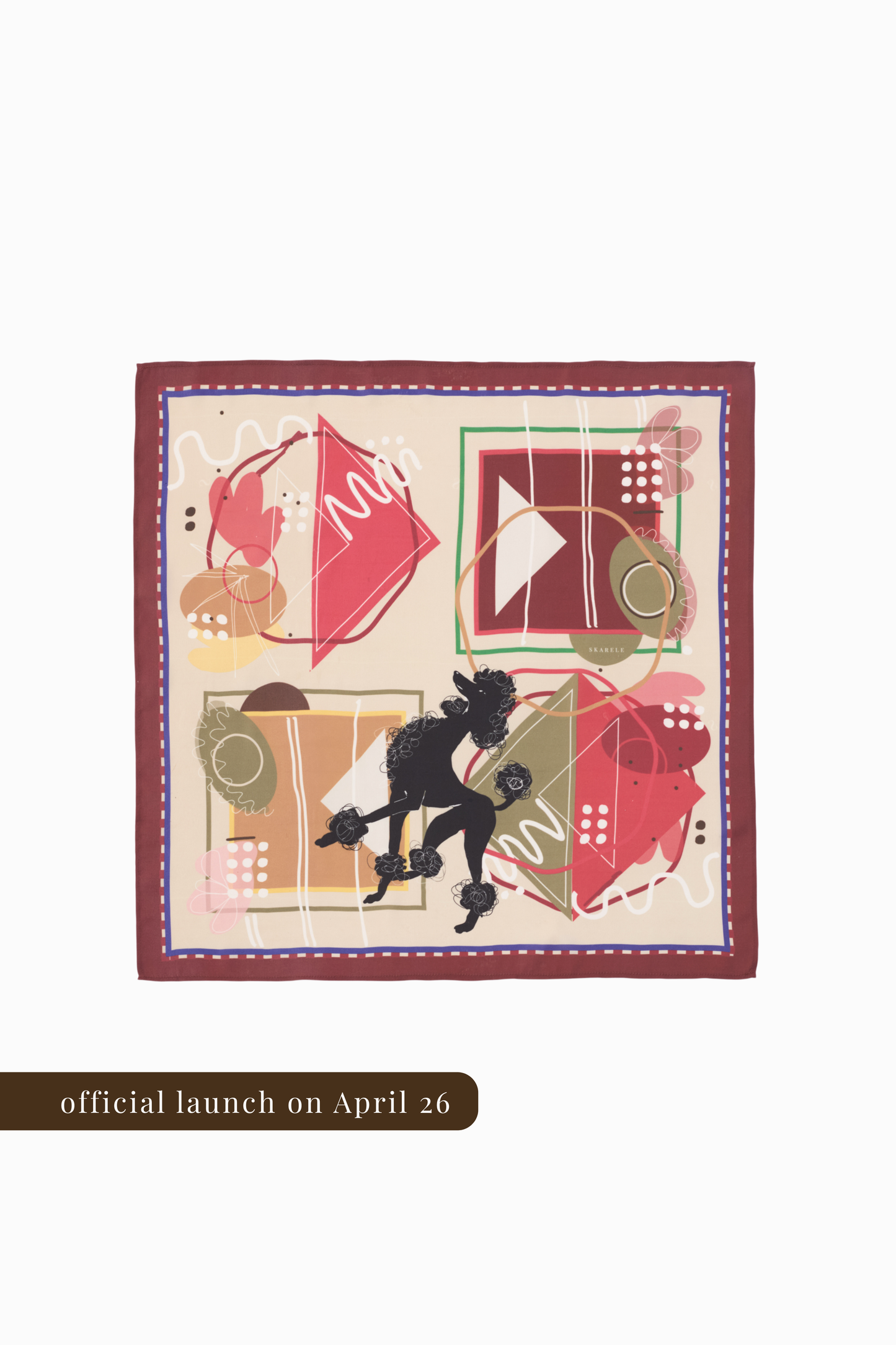 A top-down view of a square silk scarf with an abstract artistic print on a cream base. The design features a central black poodle silhouette surrounded by geometric shapes in terracotta, ochre, and olive green. It is framed by a deep burgundy border with a white-dotted inner line. A brown banner at the bottom indicates the official launch on April 26.
