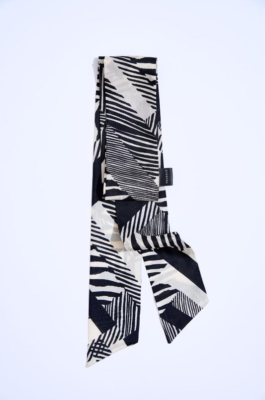 A black and white silk twilly scarf with a geometric pattern, displayed in a twisted arrangement on a plain background.