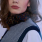 Close-up portrait of a model featuring an intricately patterned silk neck scarf paired with a striped vest, creating a sophisticated and layered high-fashion look.