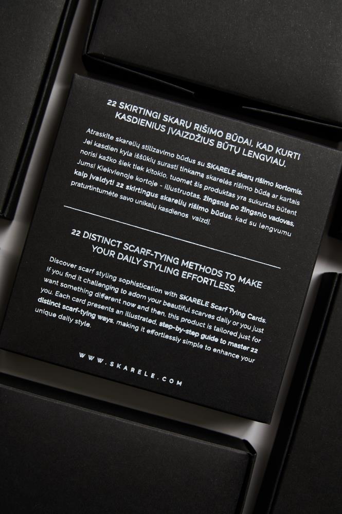 Close-up of the SKARELE Scarf Tying Cards packaging, featuring text in English and Lithuanian describing the 22 distinct scarf-tying methods and the illustrated step-by-step guide included