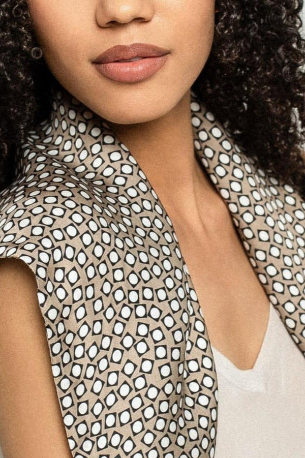 Close-up of a person wearing a patterned viscose scarf over a beige top.