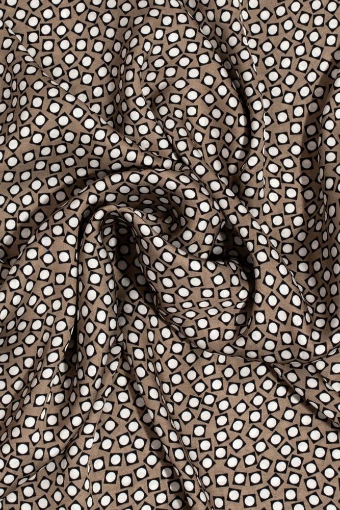 a close up view of a draped viscose scarf featuring a brown, black, and white geometric retro pattern against a clean white background. 