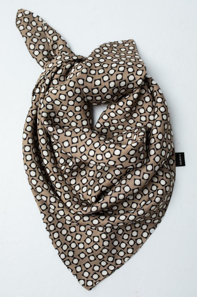 A flat lay view of a draped viscose scarf featuring a brown, black, and white geometric retro pattern against a clean white background. Shows a small black logo tag.