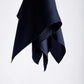 A dark, midnight blue silk scarf is elegantly suspended against a plain white background. The fabric folds create a sense of movement and sophistication.